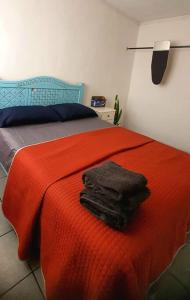 uma cama com um cobertor vermelho e duas toalhas em Hermoso Departamento Mi Pueblit0 Mágico. em Palenque