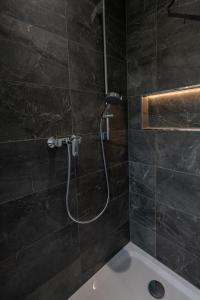 y baño con ducha y pared de azulejos negros. en Cozy City Dream Apartment mit Terrasse und Parkplatz - 90m², en Dresden