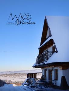 a building with a balcony in the snow at Apartamenty Za Wierchem in Bańska Wyżna