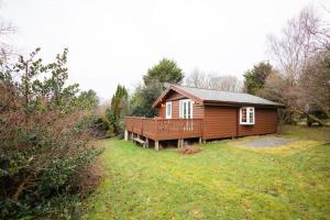 a small wooden cabin in a field of grass at Cozy Norwegian Style Log Cabin in Rural Snowdonia - 2 Bedrooms & Parking by Seren Short Stays in Ffestiniog