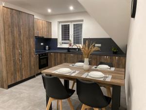 a kitchen with a wooden table and black chairs at Hradňanka Food&Beer 