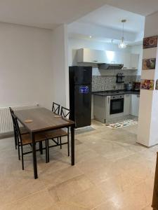 a kitchen with a table and chairs and a black refrigerator at Résidence palmerie in El Haouach