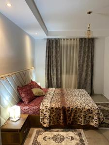 a bedroom with a bed and a table and a window at Résidence palmerie in El Haouach