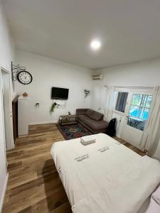 um quarto com uma cama, um sofá e um relógio em Carmel Emerald em Haifa