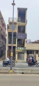 twee motorfietsen die door een straat rijden voor een gebouw bij Ramashray - Spiritual कुटिया in Ayodhya