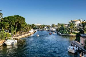 um rio com barcos com palmeiras e edifícios em Lindo apartamento con vistas al puerto Mistral em Empuriabrava