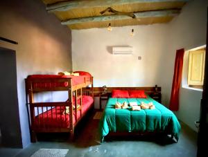 um quarto com 2 beliches com lençóis vermelhos e verdes em El Cortijo Tinogasta em Tinogasta