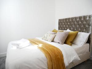 uma cama com lençóis brancos e almofadas amarelas em Modern 3 Bed 2 Bath Apartment London Denmark Hill, Camberwell, Brixton - Perfect For Long Stays em Londres