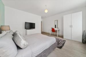 um quarto branco com uma cama e uma televisão de ecrã plano em Modern 3 Bed 2 Bath Apartment London Denmark Hill, Camberwell, Brixton - Perfect For Long Stays em Londres