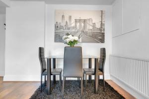 uma sala de jantar com uma mesa com cadeiras e um vaso de flores em Modern 3 Bed 2 Bath Apartment London Denmark Hill, Camberwell, Brixton - Perfect For Long Stays em Londres