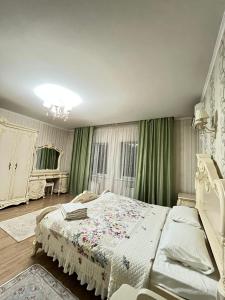 Горький парк Residence في ألماتي: غرفة نوم بسرير ابيض وستائر خضراء