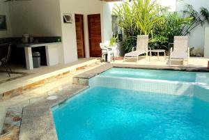 a swimming pool with two chairs and a table at Luxury Beachfront Oasis - Hermosa Palms 50 in Playa Hermosa