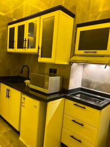 a kitchen with yellow cabinets and a microwave at استديو فاخر حي حطين بجوار البوليفارد in Riyadh