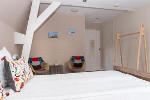 a bedroom with a white bed and two chairs at Zeeuwse Zot in Wissenkerke