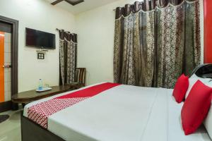 een slaapkamer met een bed met rode kussens en een televisie bij OYO Hotel President in Bathinda
