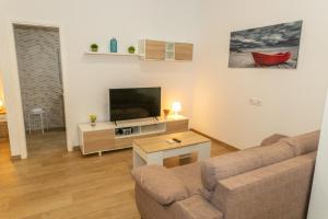 a living room with a couch and a flat screen tv at Casa Camarinero - Reformado in Barbate