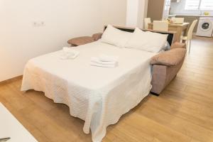 a bed with a white blanket and a couch in a room at Casa Camarinero - Reformado in Barbate