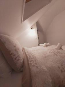 een wit bed met kussens in een witte kamer bij Duplex Cosy 1 in Gouesnou