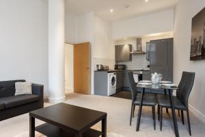 a living room with a table and chairs and a kitchen at Smart Living Apartments - One Beds in Bradford