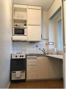 una piccola cucina con armadietti bianchi e forno a microonde di Helsinki Apartment near downtown a Helsinki