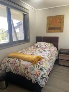 a bedroom with a bed with a floral comforter and a window at Pucon, la Capital del Sur de Chile in Pucón