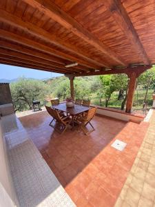 a patio with a table and chairs under a wooden roof at Cicero’s - Intero alloggio in Castelbuono