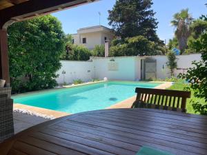 una piscina en un patio trasero con una mesa de madera en Villa Carolina, en Torre Specchia Ruggeri