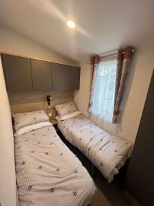 two beds in a small room with a window at The Willows in Selsey