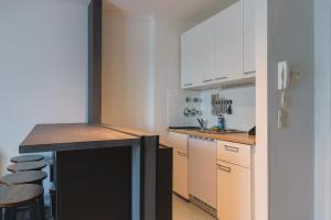 a kitchen with white cabinets and a counter and stools at K-UNITs: Lübeck Roter Löwe - City Nahes Appartement in Lübeck