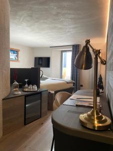 a hotel room with a bed and a desk with a lamp at LA RÊVERIE DE THUMEL - CHAMBRES in Rhêmes-Notre-Dame