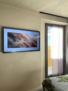 TV de pantalla plana en una pared junto a una ventana en LA RÊVERIE DE THUMEL - CHAMBRES en Rhêmes-Notre-Dame