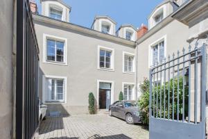 una casa blanca con un coche aparcado delante de ella en La Maison D'Hôtes Nantes Centre, en Nantes