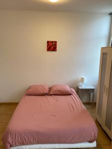 - un lit dans une chambre avec une couverture rose dans l'établissement Soulac Studio Jo Centre et Plage, à Soulac-sur-Mer