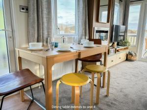 uma mesa de jantar com cadeiras e uma televisão num quarto em Little Curlew, Ynyslas, Borth em Borth