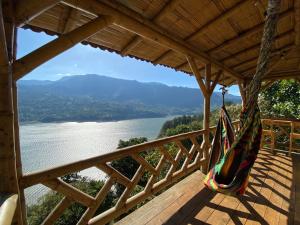a hammock on a deck overlooking a river at Cabañas Ecoturismo Evy in Macanal