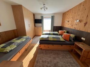 2 Betten in einem Zimmer mit Holzwänden in der Unterkunft Ferienwohnungen Unterfeld in Alpbach