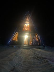 una casa illuminata nella neve di notte di Casuta mea a Stulpicani