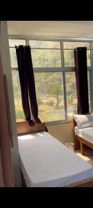 a bedroom with two beds and a large window at Utterkashi Prithvi yatra hotels in Uttarkāshi