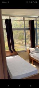 1 dormitorio con 2 camas y ventana en Utterkashi Prithvi yatra hotels, en Uttarkāshi