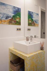 a bathroom with a sink and two paintings on the wall at Acogedor piso en pleno centro de Santander in Santander