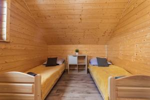 two beds in a sauna with two chairs at Domki u Magdaleny in Sztutowo