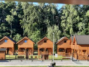 uma fila de cabanas de madeira com árvores ao fundo em Domki u Magdaleny em Sztutowo