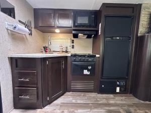 a kitchen with black cabinets and a black refrigerator at Glamping Rio Sur in Puerto Varas