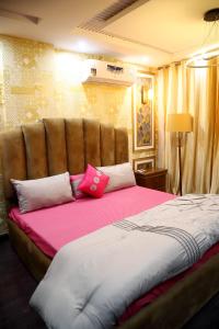 a bedroom with a large bed with pink and white pillows at Adara in Rāmkot