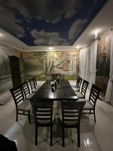 ein Esszimmer mit einem Tisch, Stühlen und einem Wandbild in der Unterkunft Villa For You Hotel in Poljanyzja