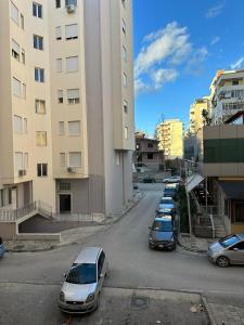 eine Reihe von Autos, die neben einem hohen Gebäude geparkt sind in der Unterkunft Melina Apartment by Elite Inn in Vlorë