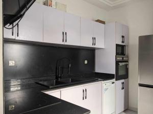 a kitchen with white cabinets and a black counter top at Dapi Home Residence in Lomé