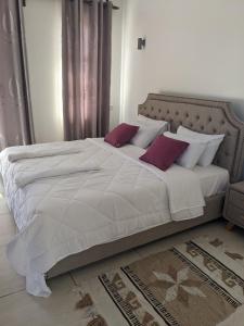 1 dormitorio con 1 cama blanca grande con almohadas rojas en Awali Villa B33, en Vipingo