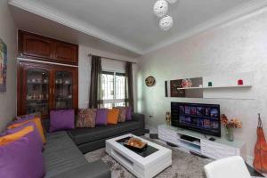 a living room with a couch and a tv at Appartement Tetouan Saniat Ramel Airport Plage Martil WIFI in Tétouan
