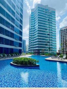 a large swimming pool in a city with tall buildings at Air Residences in the Heart of Makati City - Great for Tourists, Staycations or Working Professionals in Manila